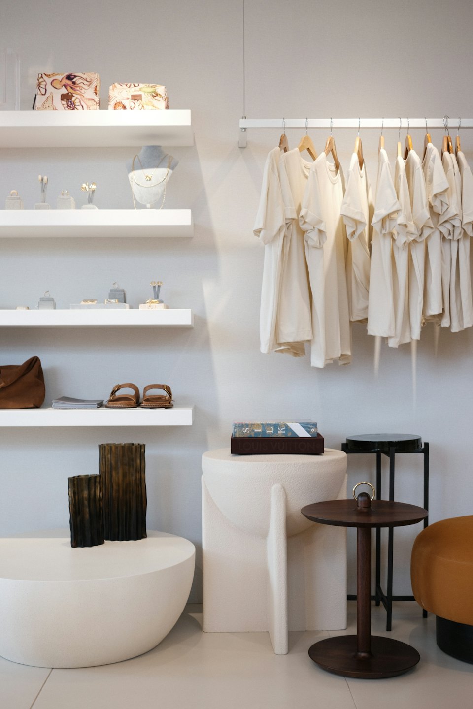 White shelves display gold jewelry, sandals, and handbags in a boutique.