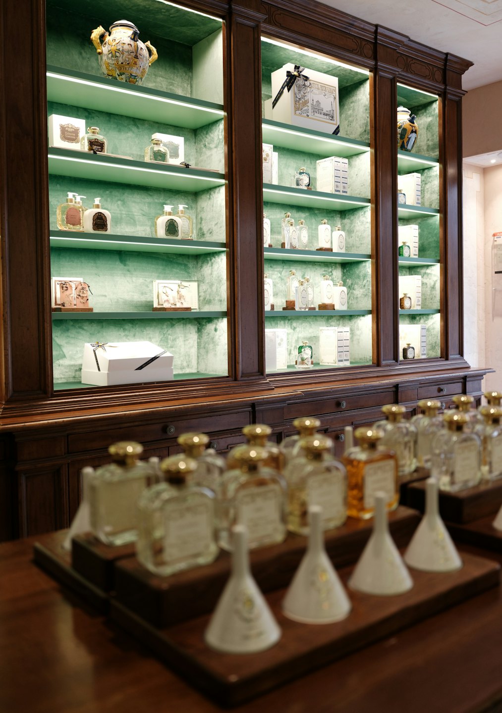 Luxury perfumes and cosmetics displayed on velvet-lined shelves.