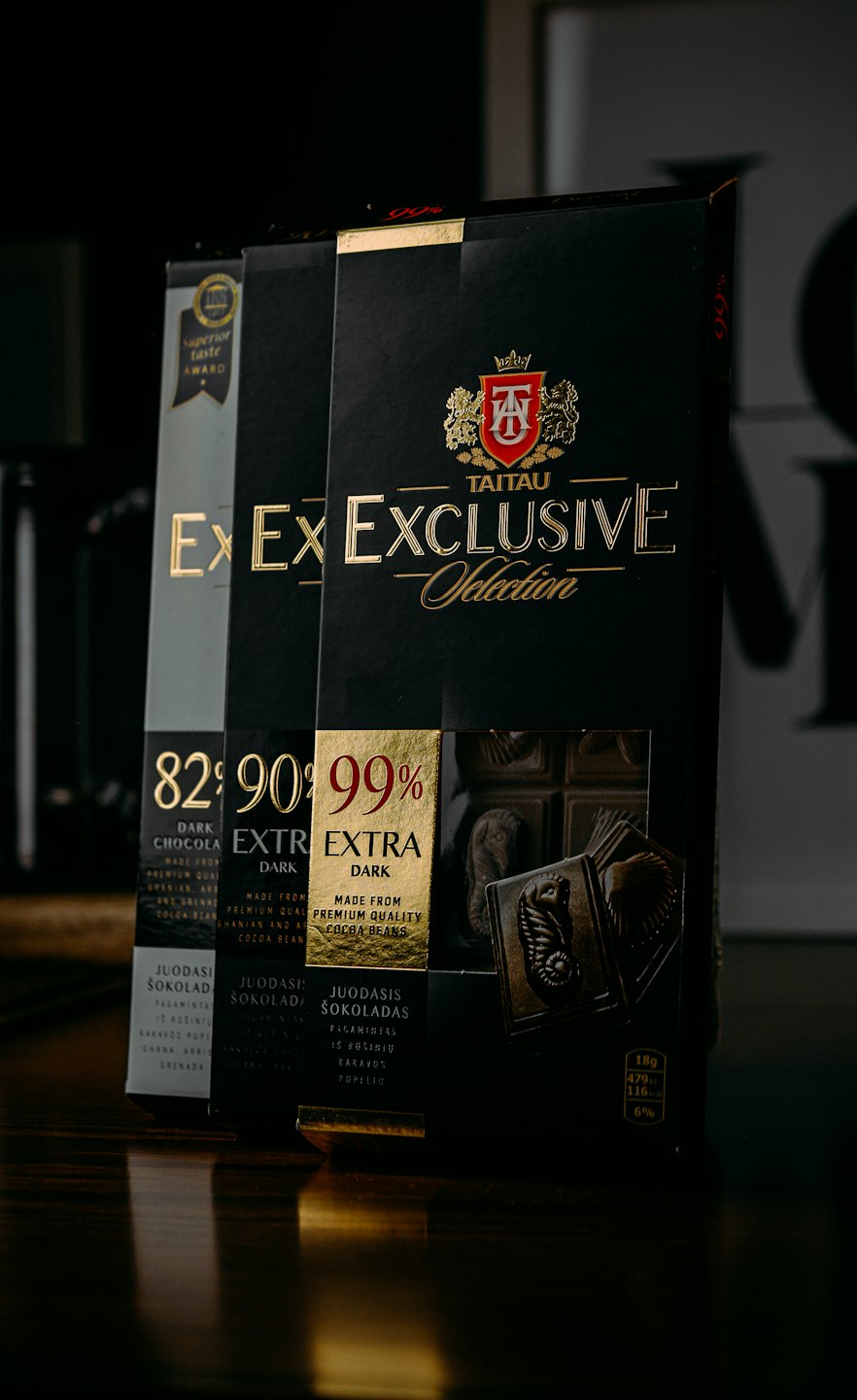 Three premium chocolate bars stand upright on a reflective surface.